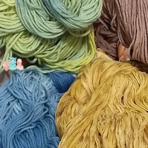 Echeveaux de laine teintés naturellement avec des colorants naturels dans les tons verts, bleus, ocre et bruns