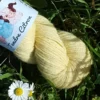 laine-merinos-tendre-citron-details Détail écheveau de laine mérinos, teinté naturellement en jaune pastel posé sur de l'herbe verte avec des pâquerettes. Laine artisanale, teinture végétale faite à la main en France