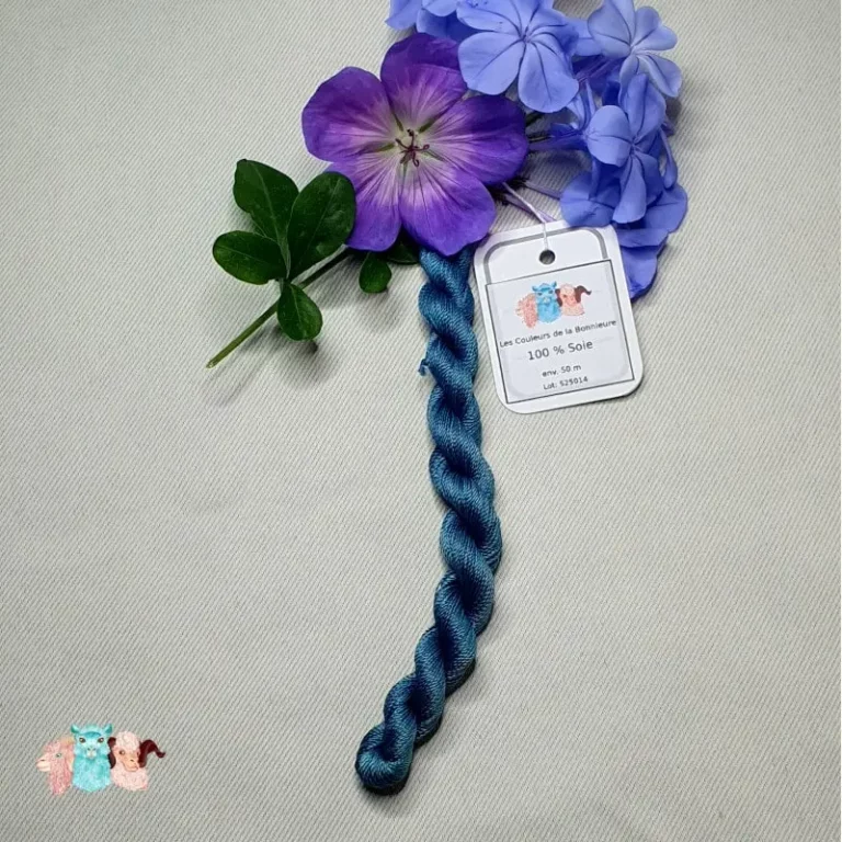 Echeveau de fil de soie bleu indigo foncé avec des fleurs sur fond gris, fabriqué en france