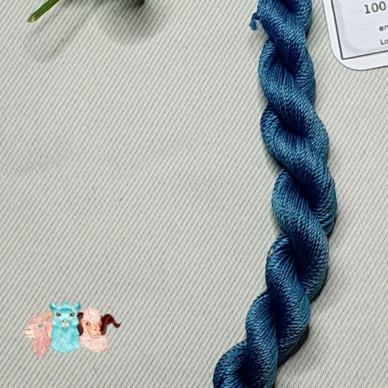 Détail d'un écheveau de fil de soie bleu indigo foncé avec des fleurs sur fond gris, fabriqué en france