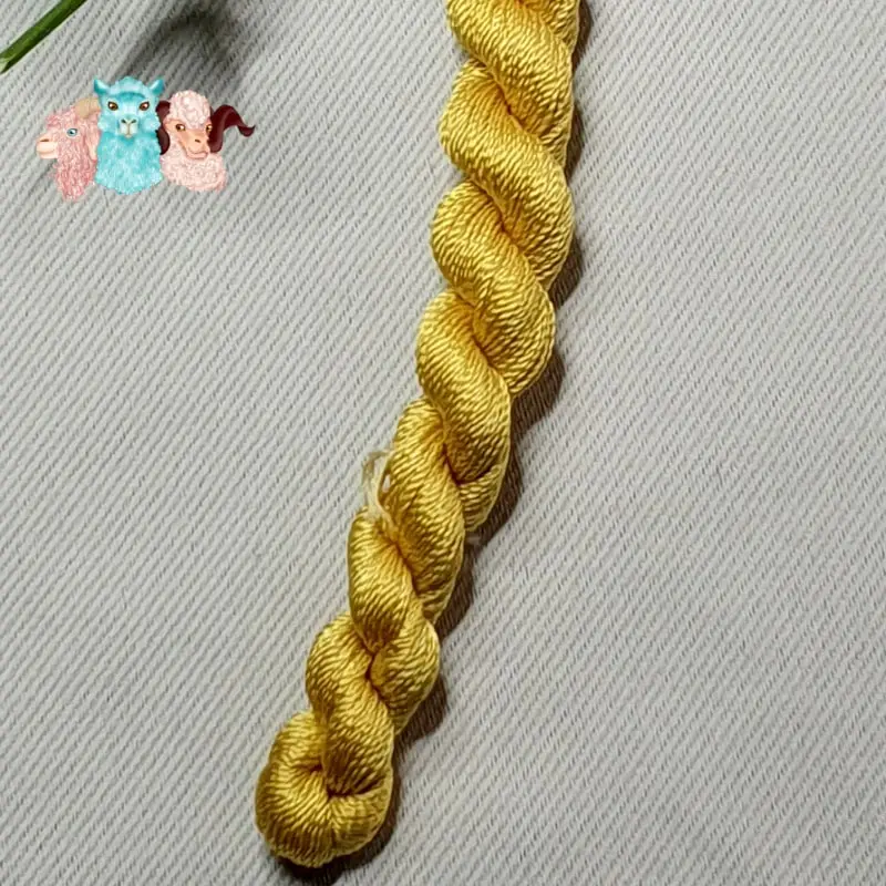 Détail d'un écheveau de fil de soie jaune foncé avec des fleurs sur fond gris, fabriqué en france