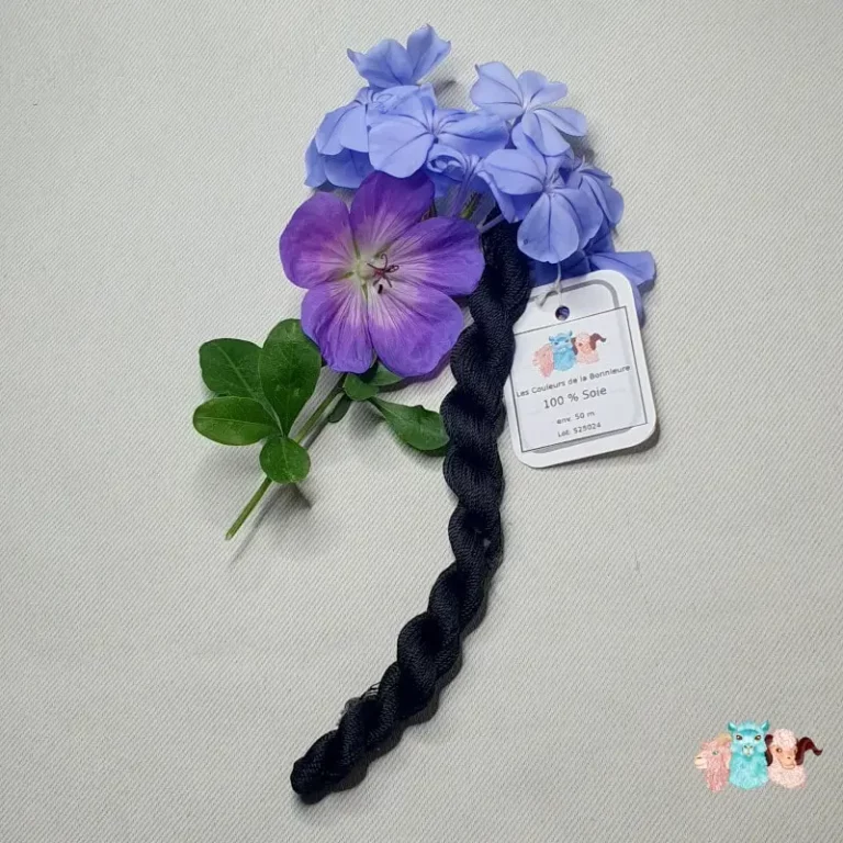 Détail d'un écheveau de fil de soie noir avec des fleurs sur fond gris, fabriqué en france