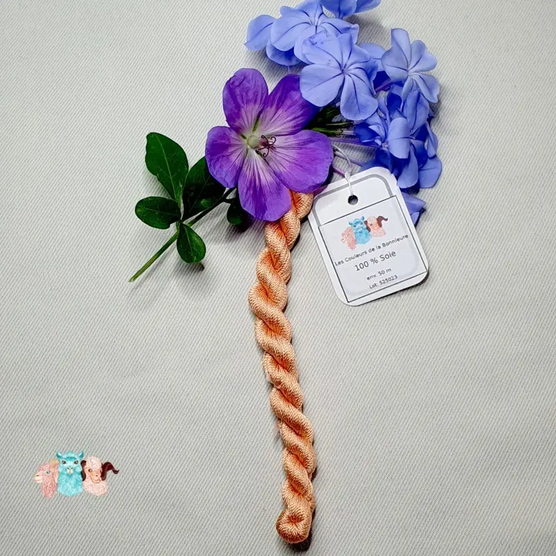 Echeveau de fil de soie orange clair avec des fleurs sur fond gris, fabriqué en france