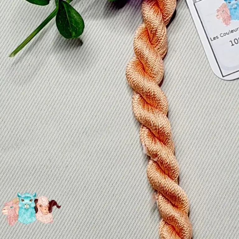 Détail écheveau de fil de soie orange clair avec des fleurs sur fond gris, fabriqué en france