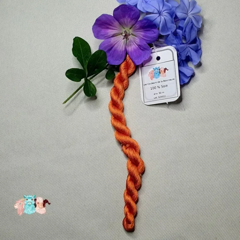 Echeveau de fil de soie orange clair avec des fleurs sur fond gris, fabriqué en france