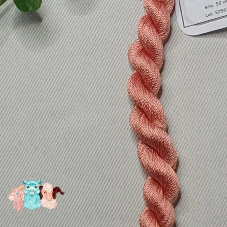 Détail d'un écheveau de fil de soie rose chair avec des fleurs sur fond gris, fabriqué en france