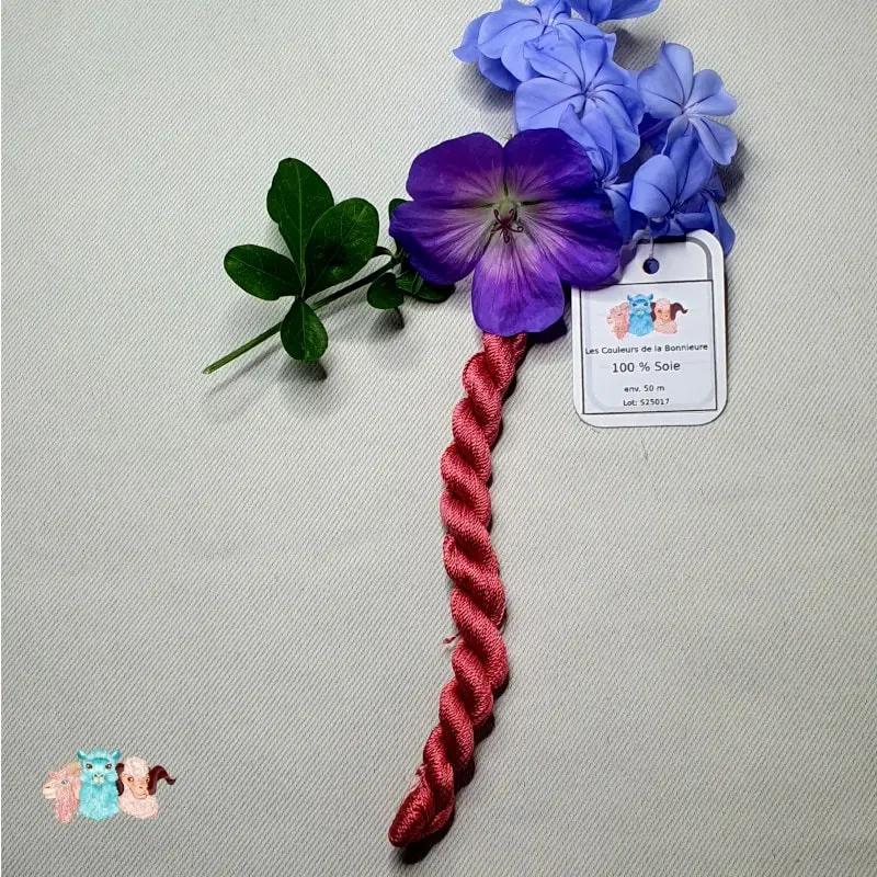 Echeveau de fil de soie rose rouge avec des fleurs sur fond gris, fabriqué en france