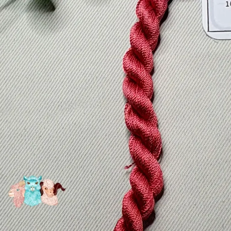 Détail d'un écheveau de fil de soie rose rouge avec des fleurs sur fond gris, fabriqué en france