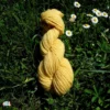 Echeveau de laine française fil mèche fin coloris jaune sur fond d'herbe avec des fleurs fabriqué en france