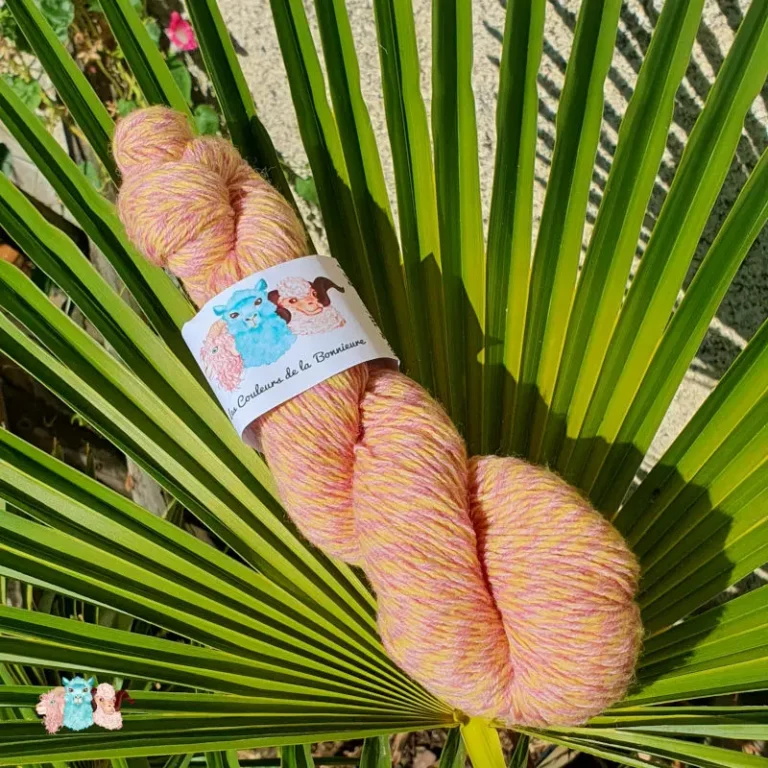 Echeveau de laine chinée violet et jaune, sur fond de feuilles vert, fabrication française