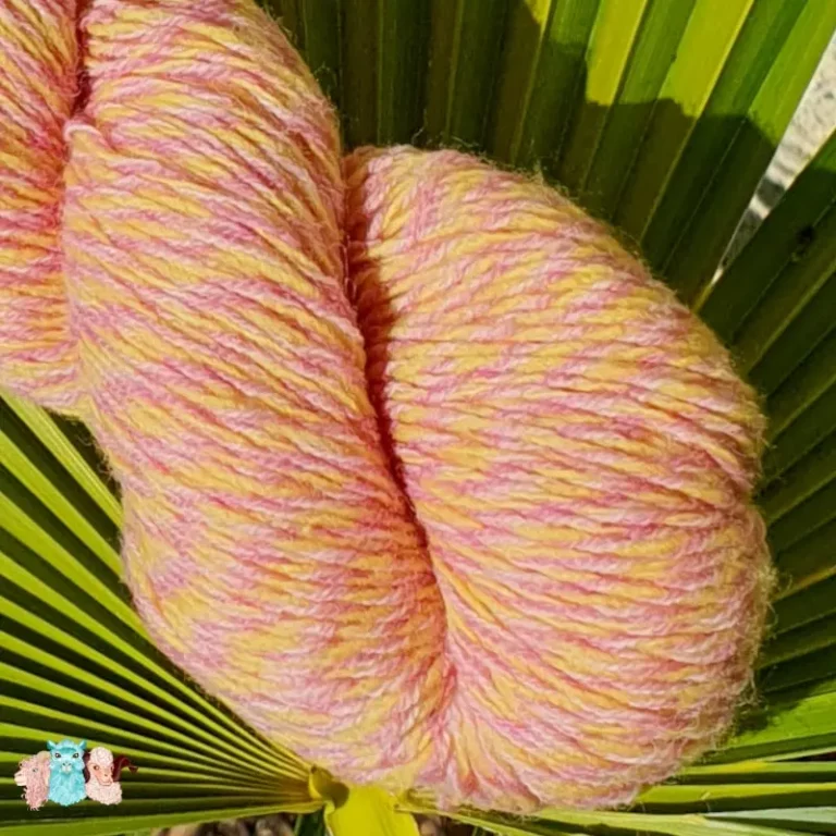 Gros plan d'un écheveau de laine chinée violet et jaune, sur fond de feuilles vert, fabrication française