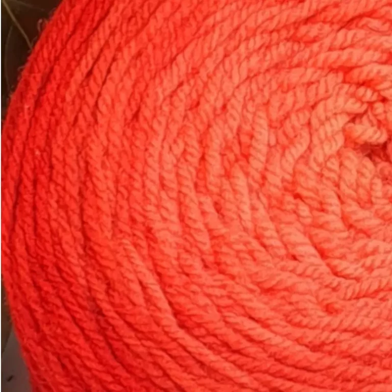 Gros plan d'une pelote de laine de coloris de l'orange foncé à l'orange clair.