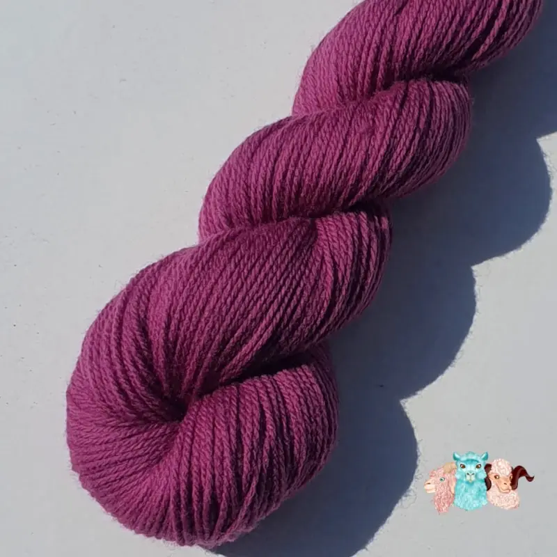 Détail d'un écheveau de laine mérinos unie, teinté naturellement en violet foncé posé sur fond gris, teinture végétale faite à la main en France