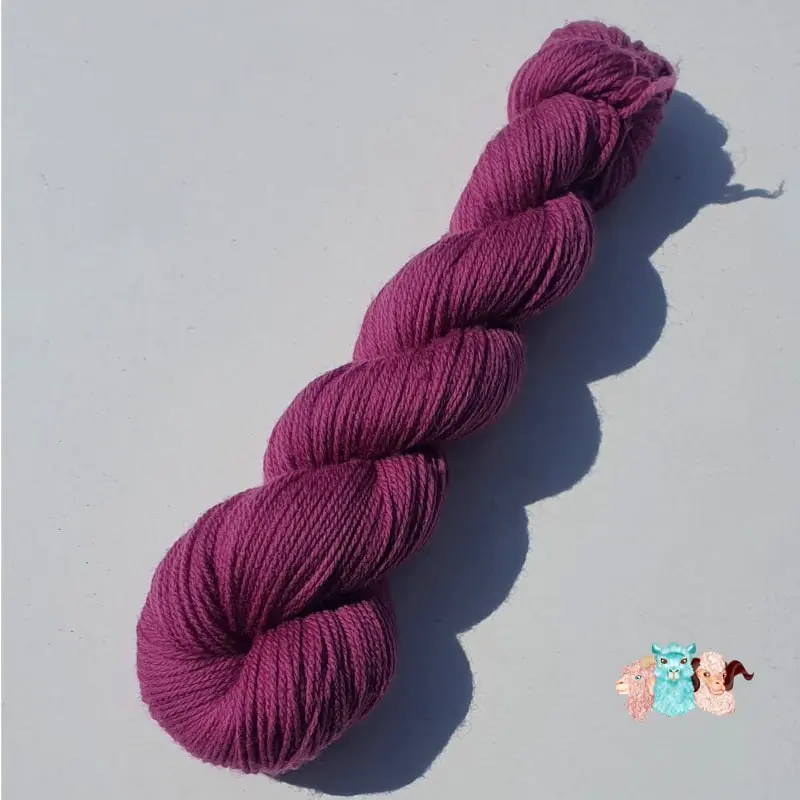 Echeveau de laine mérinos unie, teinté naturellement en violet foncé posé sur fond gris, teinture végétale faite à la main en France