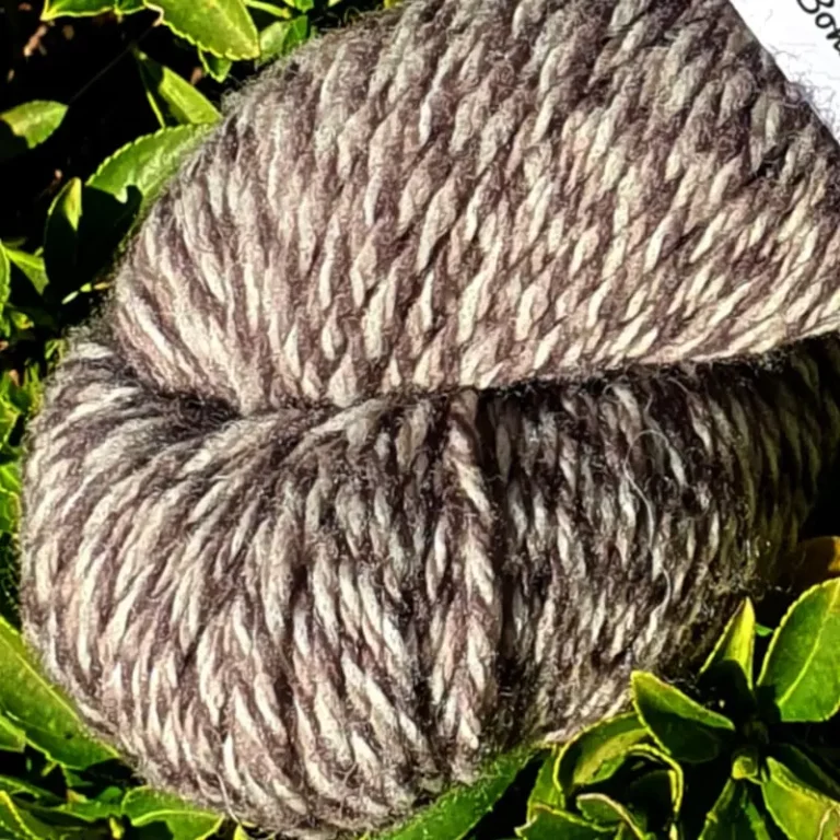 Gros plan d'un écheveau de laine chinée grise, sur fond de feuilles vert, fabrication française