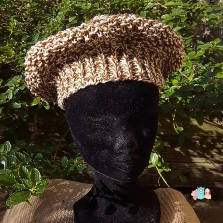 Bonnet, type béret, présenté de face sur une tête d'exposition, en laine mérinos teinté en bicolore marron-écru, sur un fond naturel.