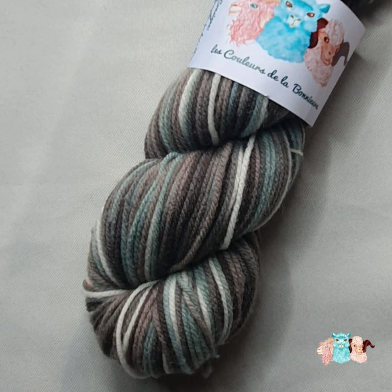 Détail écheveau de laine mérinos multicolore gris bleuté avec des nuances sur un fond gris