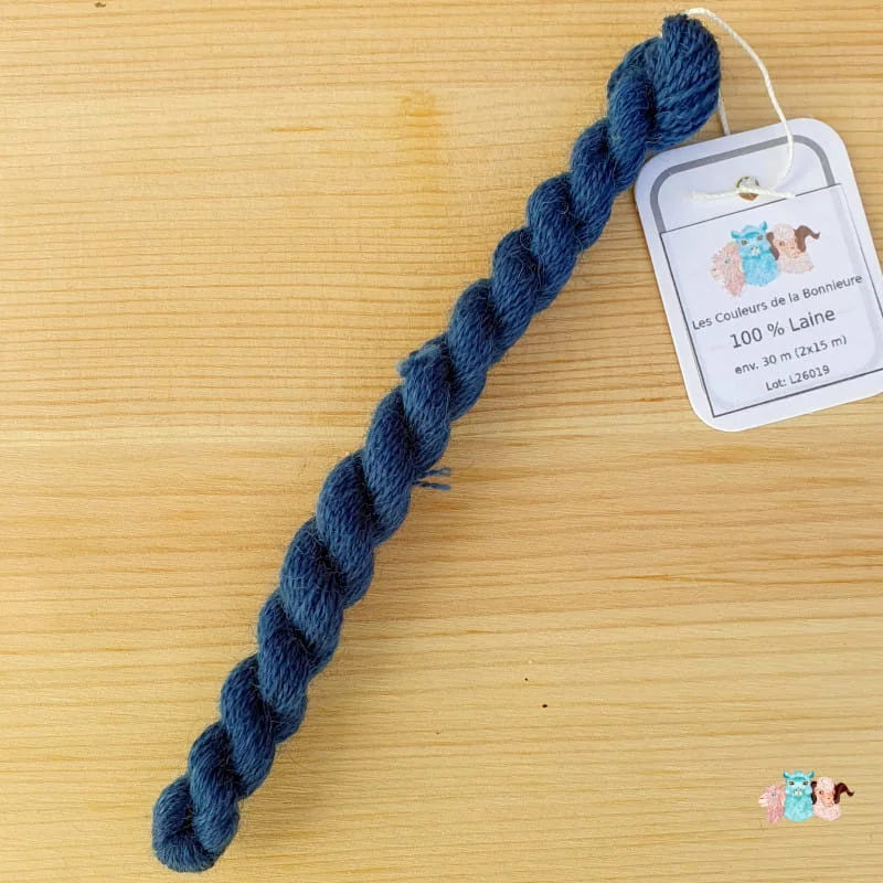 Echeveau de fil de laine bleu foncé sur fond bois, fabriqué en france