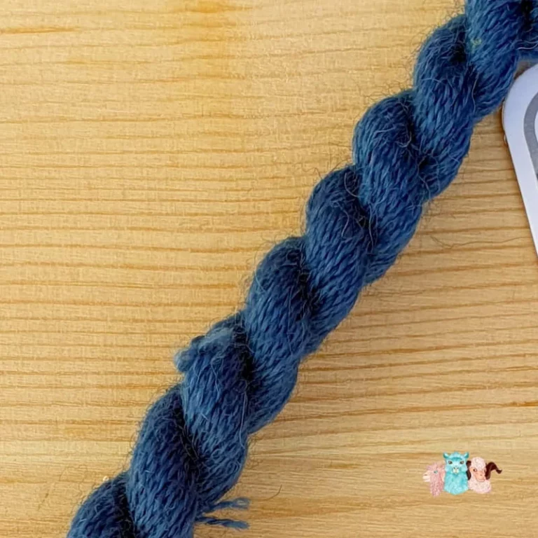 Détail d'un écheveau de fil de laine bleu foncé sur fond bois, fabriqué en france
