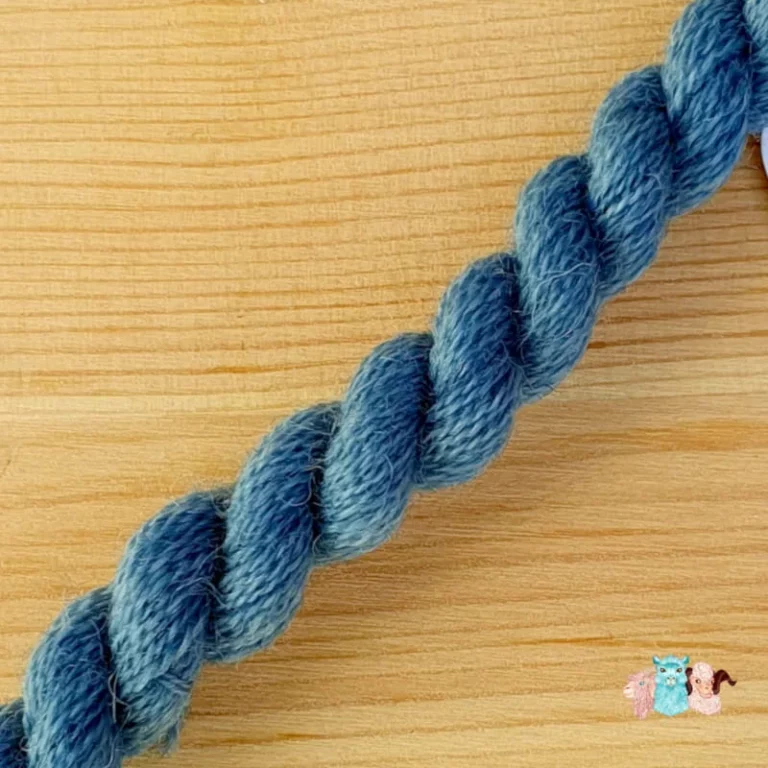 Détail d'un écheveau de fil de laine bleu moyen sur fond bois, fabriqué en france