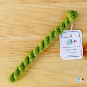 Détail d'un écheveau de fil de laine vert clair sur fond bois, fabriqué en france