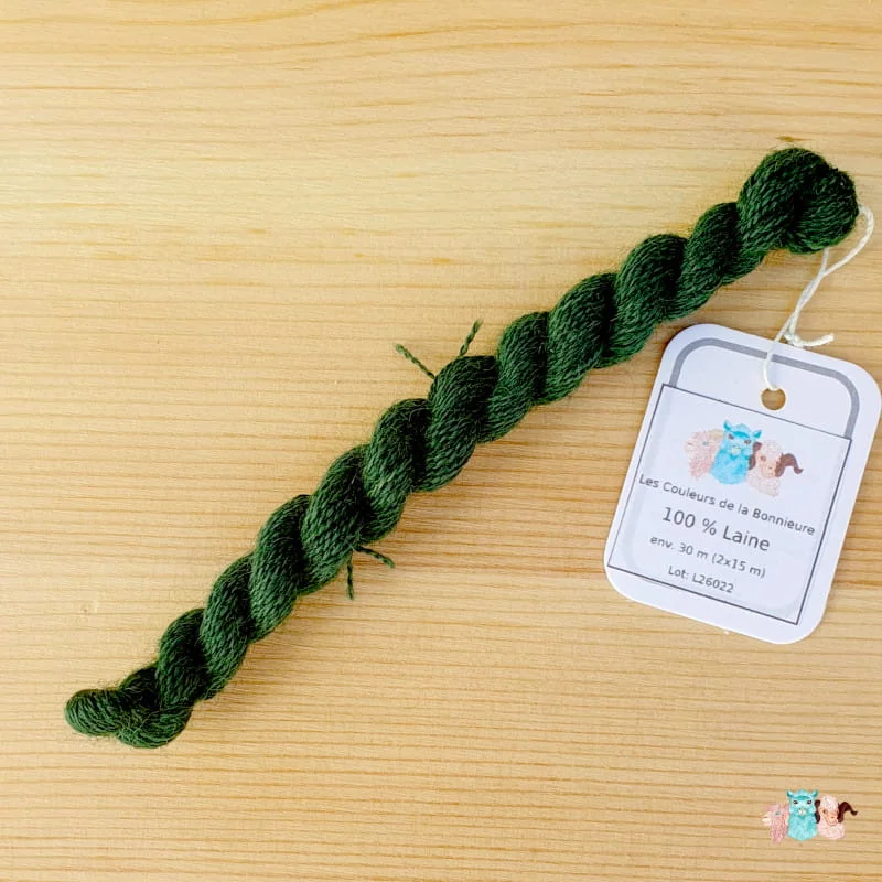 Echeveau de fil de laine vert foncé sur fond bois, fabriqué en france