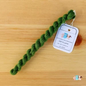 Echeveau de fil de laine vert moyen sur fond bois, fabriqué en france