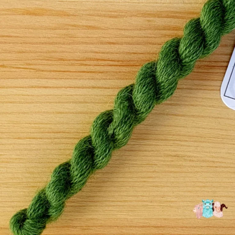 Détail d'un écheveau de fil de laine vert moyen sur fond bois, fabriqué en france