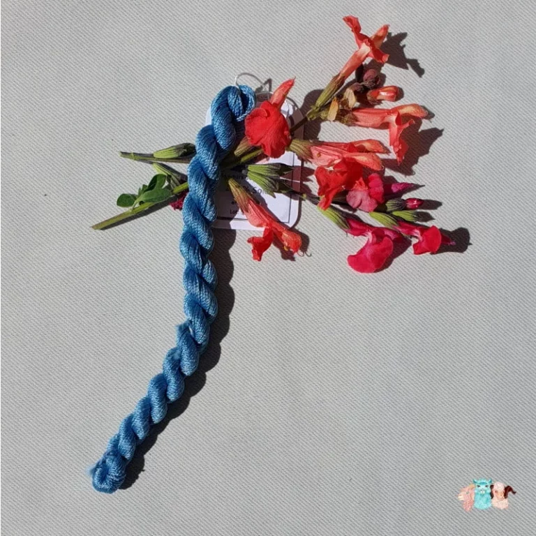 Echeveau de fil de soie bleu indigo clair avec des fleurs sur fond gris, fabriqué en france