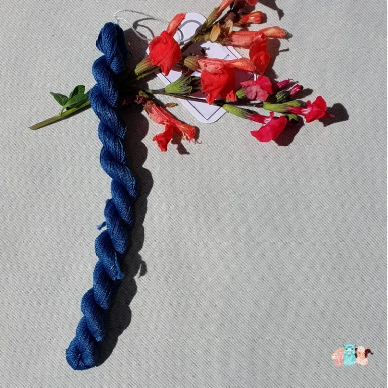 Echeveau de fil de soie bleu indigo foncé avec des fleurs sur fond gris, fabriqué en france