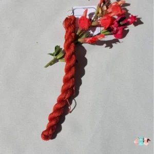 Echeveau de fil de soie orange foncé avec des fleurs sur fond gris, fabriqué en france