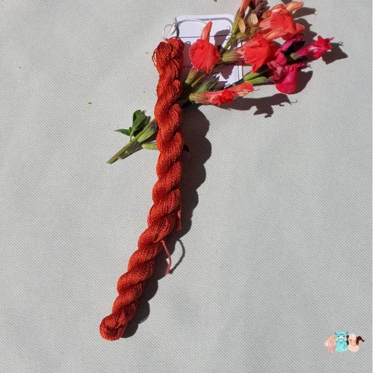 Echeveau de fil de soie orange foncé avec des fleurs sur fond gris, fabriqué en france