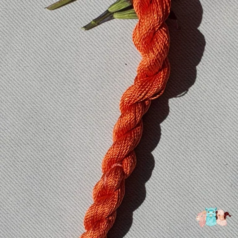 Détail d'un écheveau de fil de soie orange moyen avec des fleurs sur fond gris, fabriqué en france