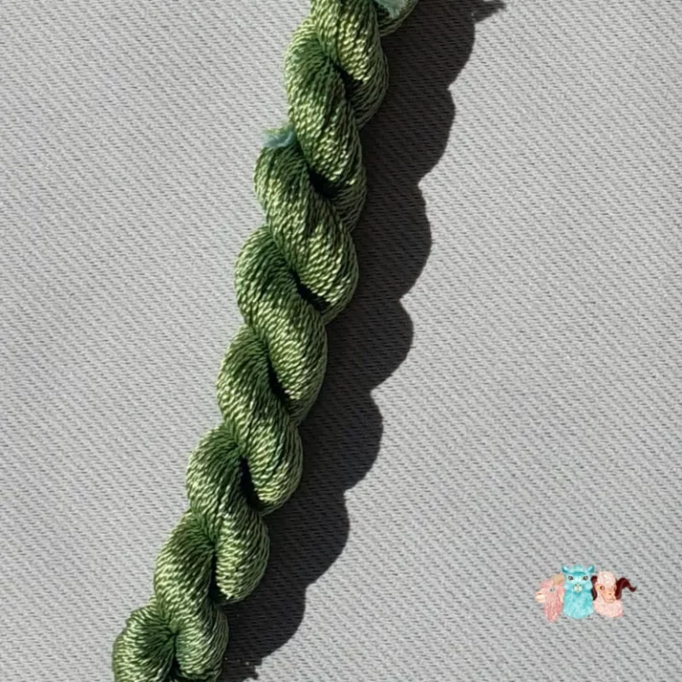 Détail d'un écheveau de fil de soie vert clair sur fond gris, fabriqué en france