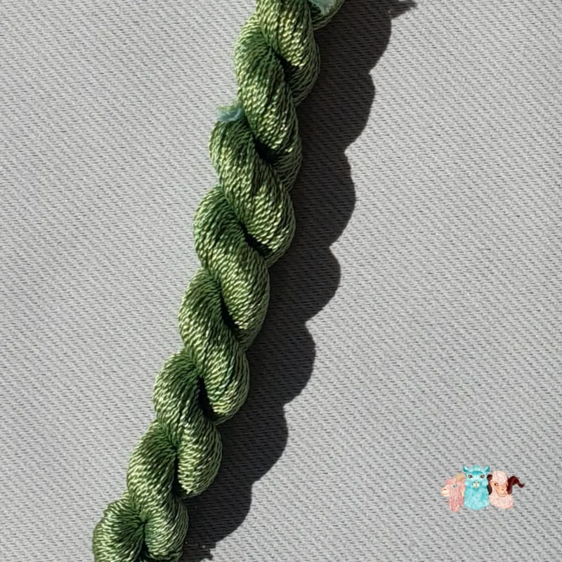 Détail d'un écheveau de fil de soie vert clair sur fond gris, fabriqué en france