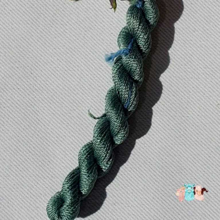 Détail d'un écheveau de fil de soie vert foncé sur fond gris, fabriqué en france