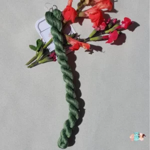 Echeveau de fil de soie vert moyen avec des fleurs rouge sur fond gris, fabriqué en france