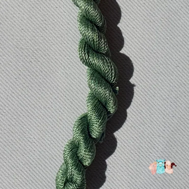 Détail d'un écheveau de fil de soie vert moyen sur fond gris, fabriqué en france