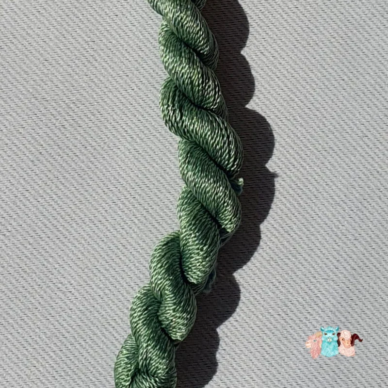 Détail d'un écheveau de fil de soie vert moyen sur fond gris, fabriqué en france