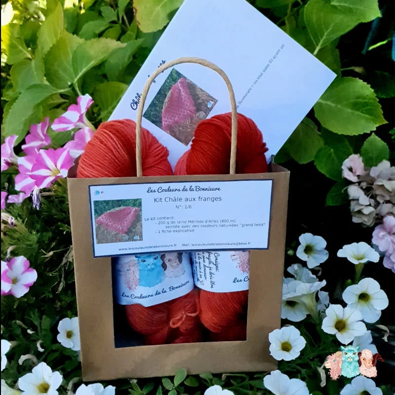 Kit de châle avec des franges en dégradé rouge sur un botte de paille.